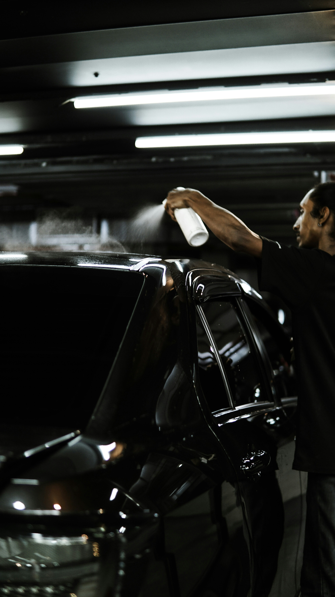 Auto detailer spraying ceramic coating on a vehicle