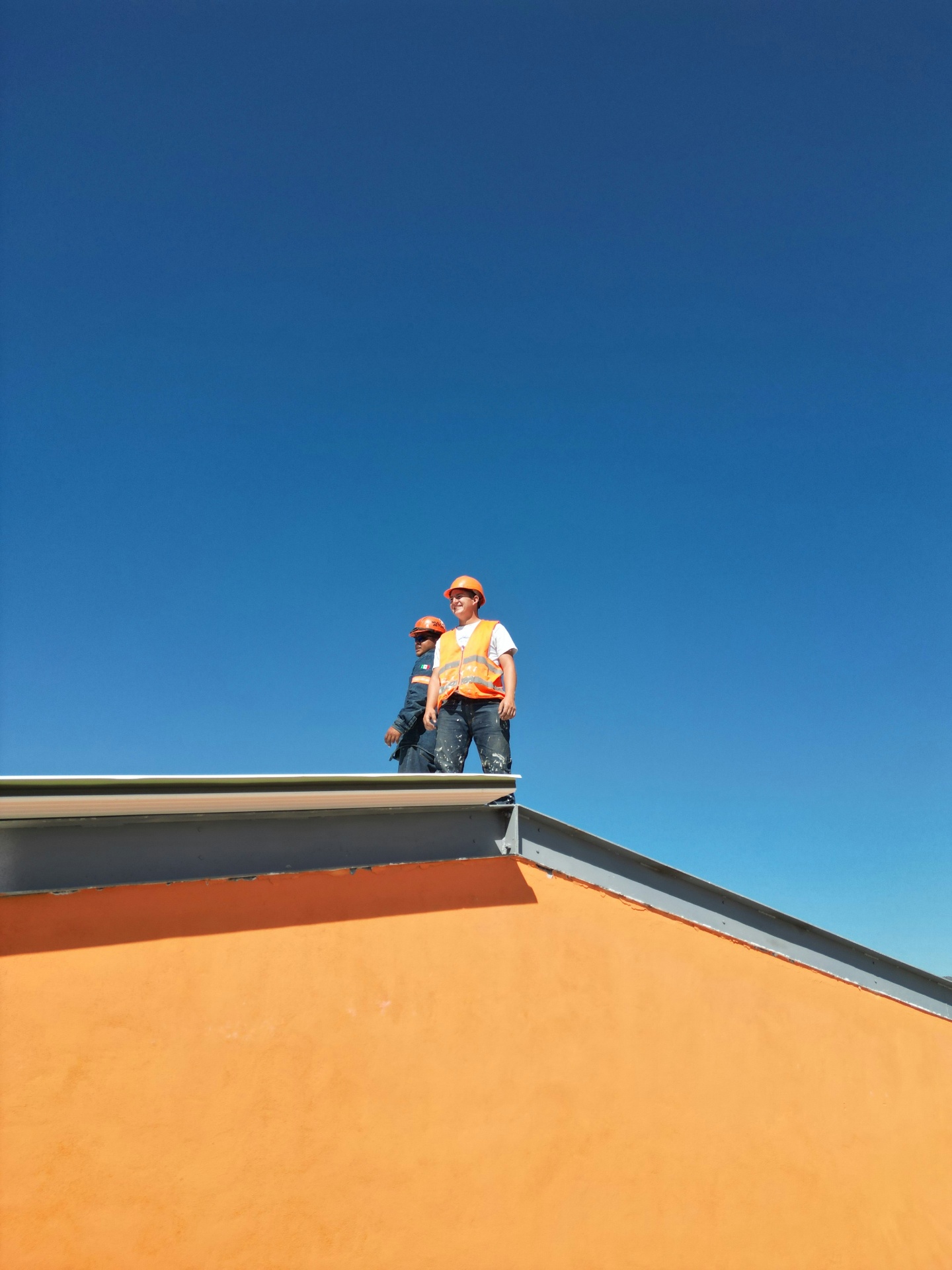 Roofers in safety vests standing on a commercial rooftop